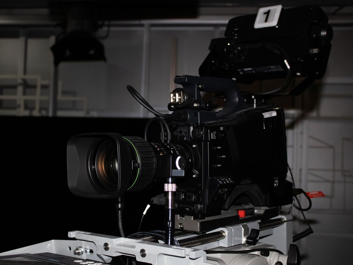 Broadcast studio camera on a pedestal in a darkened studio
