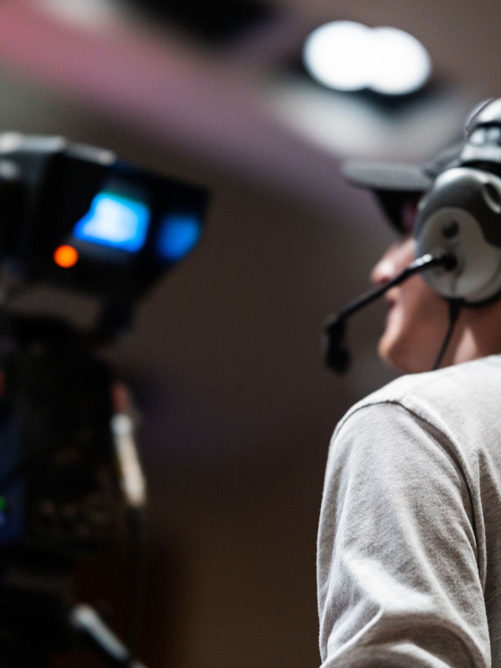Camera operator wearing an intercom headset behind a studio camera