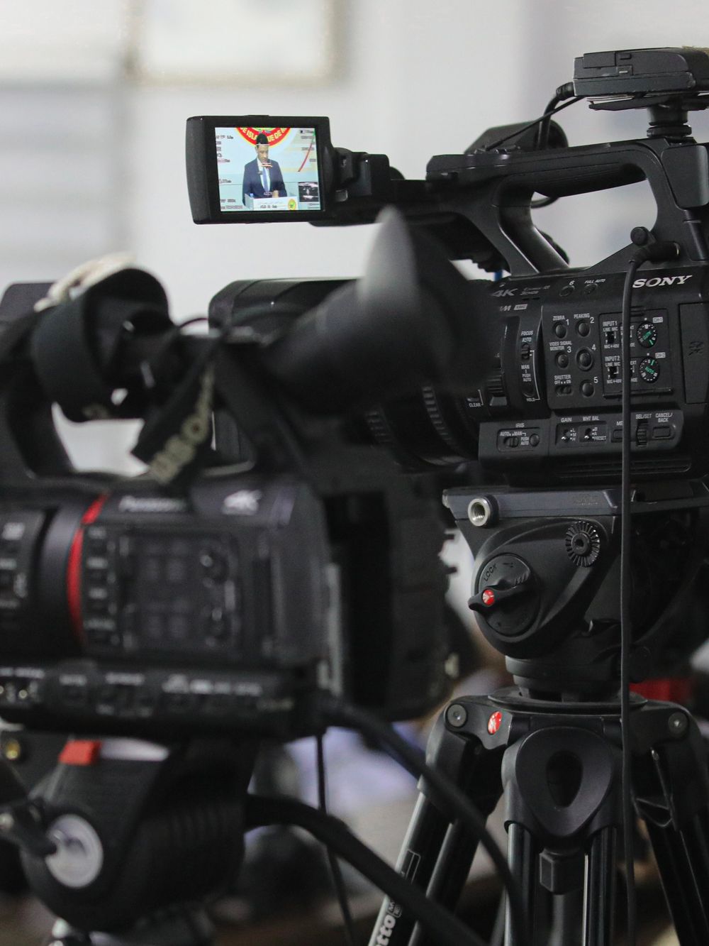 Professional broadcast camcorder on a tripod with its viewfinder lit