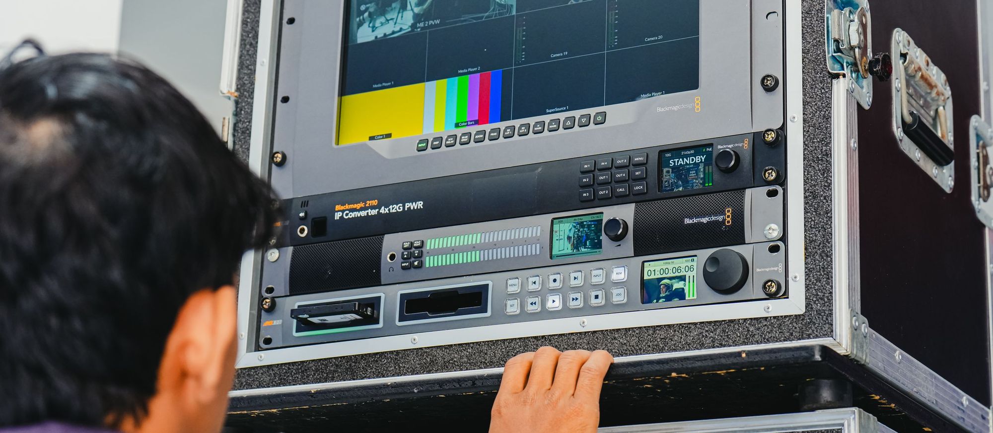 Technician operating broadcast recorders and a monitor in a flight-case rack